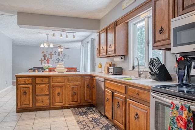 279 Ardelean Dr, Owosso, MI 48867 - kitchen with stainless steel appliances, brown cabinets, a peninsula, light countertops, and light tile patterned floors