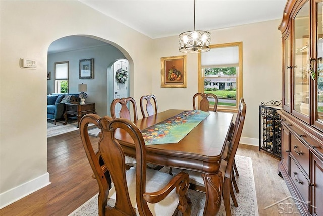 2816 Chippewa Ln, Midland, MI 48640 - dining room featuring arched walkways, healthy amount of natural light, light wood-type flooring, and a chandelier