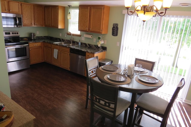 3577 Greenly Ct, Holland, MI 49424 - kitchen featuring stainless steel appliances, dark countertops, a chandelier, dark wood-style flooring, and brown cabinets