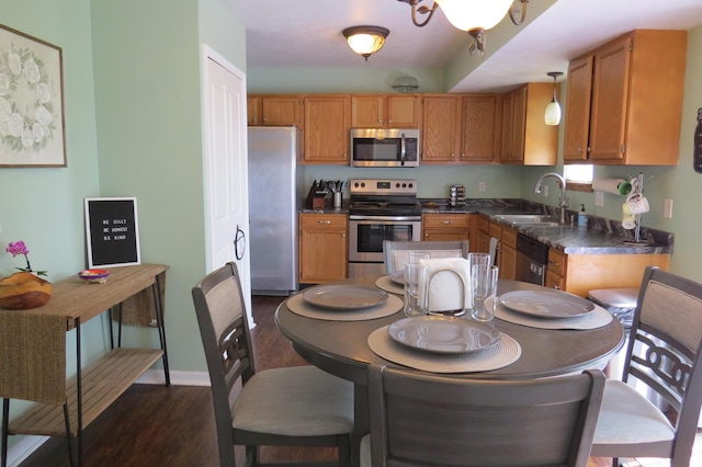3577 Greenly Ct, Holland, MI 49424 - kitchen featuring stainless steel appliances, dark countertops, dark wood-style floors, and brown cabinetry