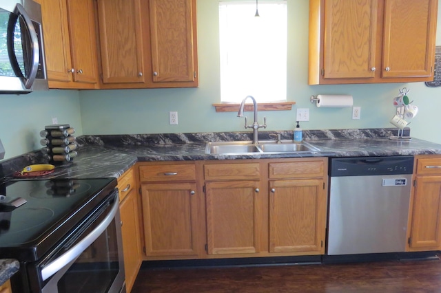 3577 Greenly Ct, Holland, MI 49424 - kitchen featuring appliances with stainless steel finishes, dark countertops, dark wood-style flooring, and brown cabinetry