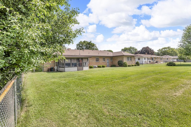 1515 Kensington Dr, Jackson, MI 49203 - rear view of property with a sunroom, a fenced backyard, and brick siding
