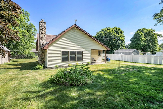863 E Wilcox Ave, White Cloud, MI 49349 - rear view of property featuring a chimney and a patio area
