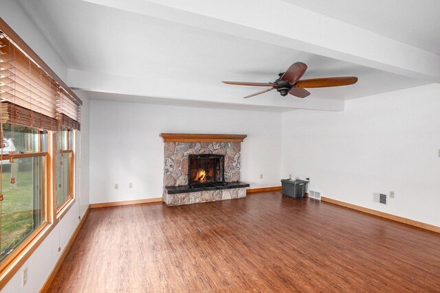 863 E Wilcox Ave, White Cloud, MI 49349 - unfurnished living room featuring wood finished floors, plenty of natural light, a fireplace, and a ceiling fan