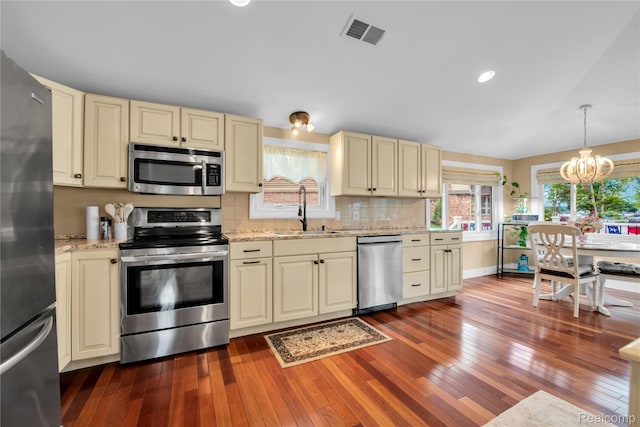 8320 Lagoon St, Commerce Twp, MI 48382 - kitchen with appliances with stainless steel finishes, cream cabinetry, dark wood-style floors, a chandelier, and recessed lighting