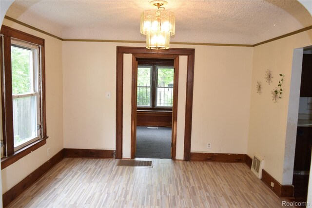 316 W Rankin St, Flint, MI 48505 - unfurnished dining area featuring light wood-style floors, plenty of natural light, a chandelier, a textured ceiling, and crown molding