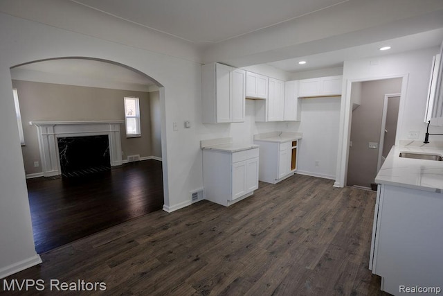 21212 Universal Ave, Eastpointe, MI 48021 - kitchen with light stone counters, arched walkways, white cabinets, dark wood-type flooring, and recessed lighting