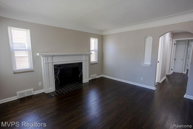 21212 Universal Ave, Eastpointe, MI 48021 - unfurnished living room featuring dark wood-style flooring, healthy amount of natural light, arched walkways, and a high end fireplace