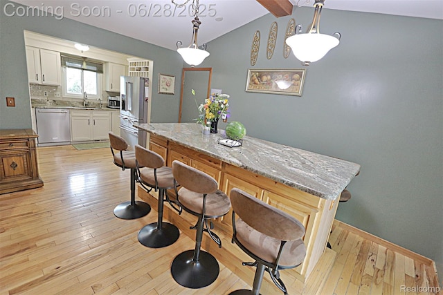 1640 High Pointe Dr, Commerce Twp, MI 48390 - kitchen with stainless steel appliances, white cabinetry, light wood-style floors, and pendant lighting