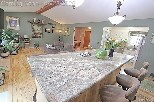 1640 High Pointe Dr, Commerce Twp, MI 48390 - kitchen featuring light wood-type flooring, a center island, light stone counters, stainless steel dishwasher, and a kitchen breakfast bar