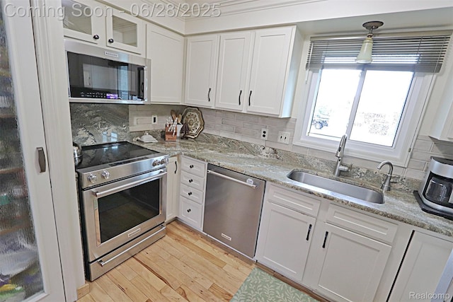 1640 High Pointe Dr, Commerce Twp, MI 48390 - kitchen featuring stainless steel appliances, white cabinetry, backsplash, light wood-style floors, and light stone counters