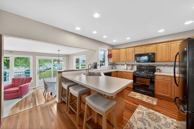 70749 Sunset Blvd, Union, MI 49130 - kitchen featuring black appliances, a peninsula, a kitchen bar, light countertops, and healthy amount of natural light