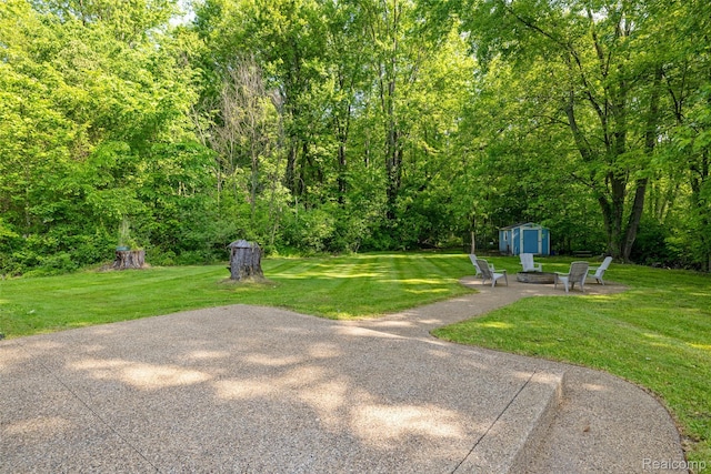 6590 Swartout Rd, Clay, MI 48001 - view of green lawn featuring a storage unit, an outdoor fire pit, and a patio area