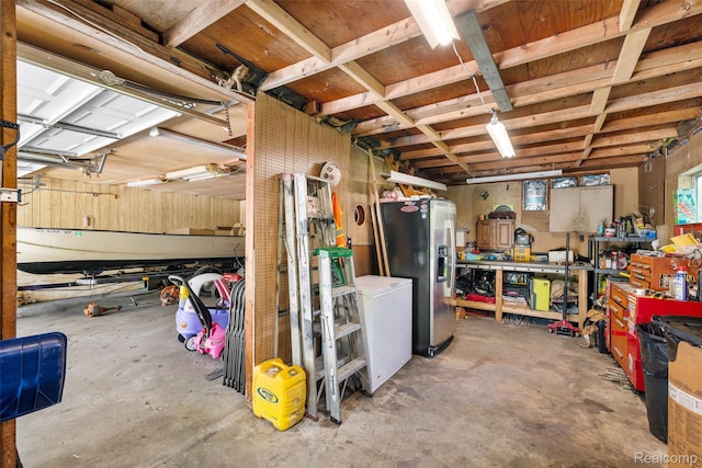 6590 Swartout Rd, Clay, MI 48001 - below grade area featuring stainless steel refrigerator with ice dispenser, a workshop area, and a garage