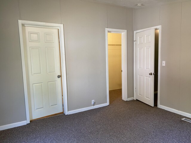 6317 E 76th St, Newaygo, MI 49337 - unfurnished bedroom featuring dark colored carpet and a walk in closet