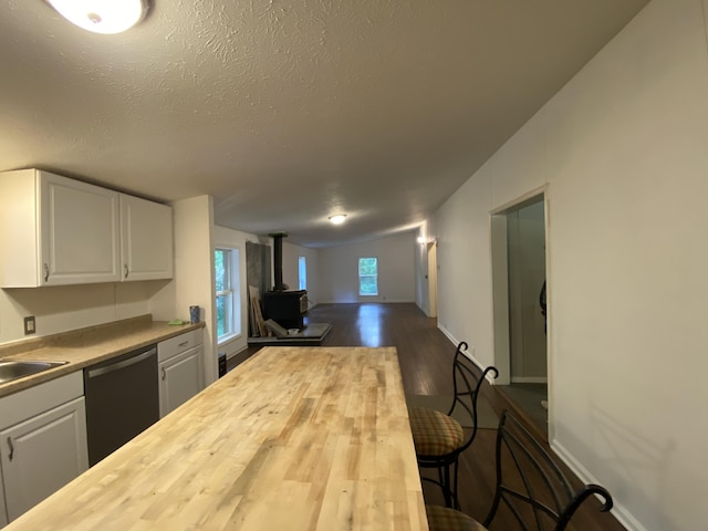 6317 E 76th St, Newaygo, MI 49337 - kitchen featuring stainless steel dishwasher, butcher block countertops, a wood stove, white cabinetry, and a textured ceiling