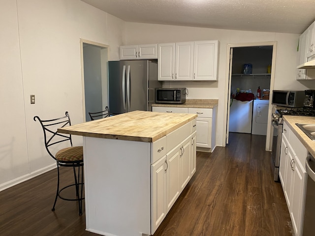 6317 E 76th St, Newaygo, MI 49337 - kitchen with appliances with stainless steel finishes, vaulted ceiling, dark wood-style flooring, washer and dryer, and white cabinets