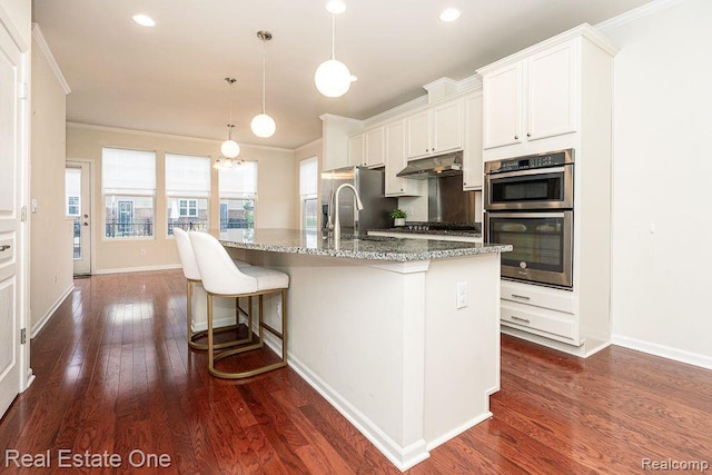 2669 Helmsdale Cir, Rochester, MI 48307 - kitchen with crown molding, stainless steel appliances, dark wood-style flooring, a kitchen island with sink, and light stone counters