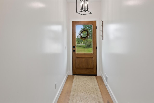 6581 Timpson Ave SE, Alto, MI 49302 - doorway to outside featuring light wood finished floors and a chandelier