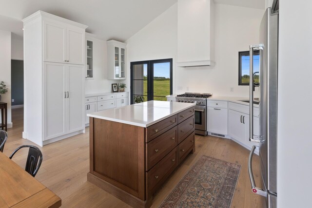 6581 Timpson Ave SE, Alto, MI 49302 - kitchen featuring stainless steel appliances, white cabinets, light countertops, light wood-type flooring, and high vaulted ceiling