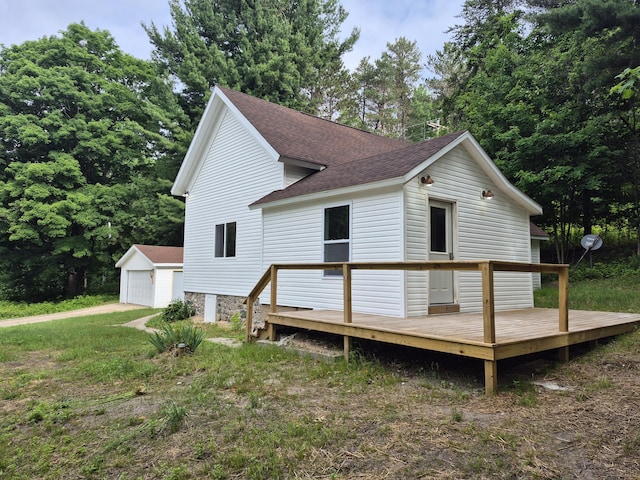 17324 11 Mile Rd, Leroy, MI 49655 - rear view of property featuring a shingled roof, a deck, a garage, and an outdoor structure