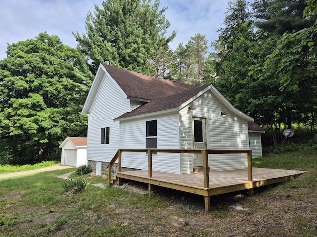17324 11 Mile Rd, Leroy, MI 49655 - view of property exterior with a wooden deck, an outdoor structure, a detached garage, and roof with shingles
