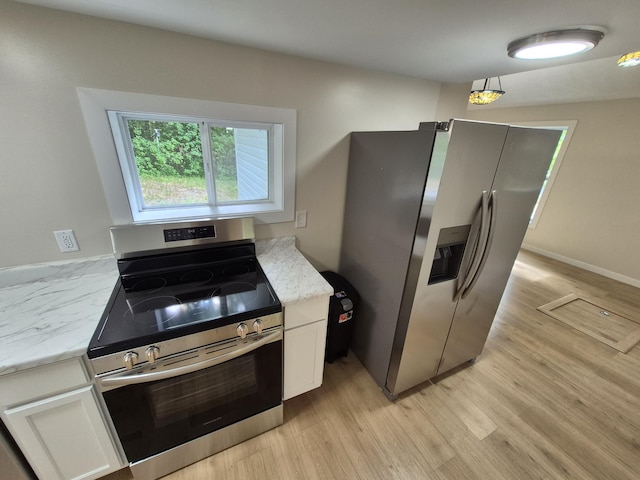 17324 11 Mile Rd, Leroy, MI 49655 - kitchen featuring stainless steel appliances, white cabinetry, light wood-style flooring, and light stone counters