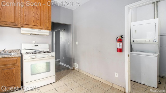 21005 Westview Ave, Ferndale, MI 48220 - kitchen featuring gas range gas stove, stacked washer / dryer, under cabinet range hood, and light tile patterned floors