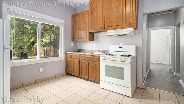 21005 Westview Ave, Ferndale, MI 48220 - kitchen with white appliances, under cabinet range hood, light tile patterned flooring, light countertops, and brown cabinets