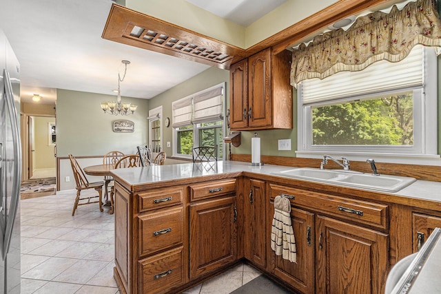 4650 Rollridge Ave, Kalamazoo, MI 49004 - kitchen with brown cabinets, a chandelier, decorative light fixtures, light tile patterned floors, and a peninsula