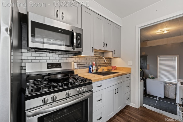 4860 Lindholm Dr, White Lake, MI 48383 - kitchen featuring appliances with stainless steel finishes, wood counters, dark wood-style flooring, and backsplash