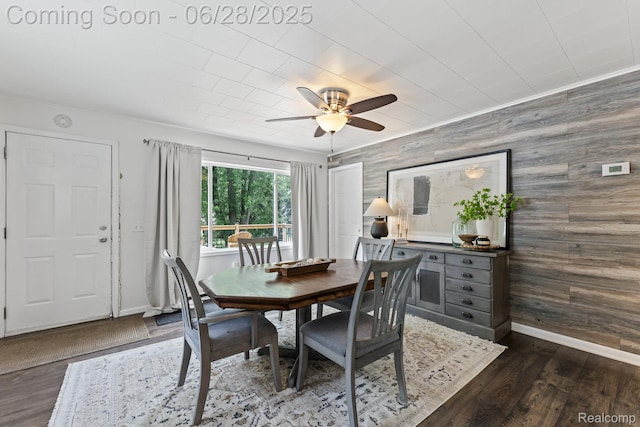 4860 Lindholm Dr, White Lake, MI 48383 - dining space featuring ceiling fan, dark wood-style flooring, an accent wall, and wood walls