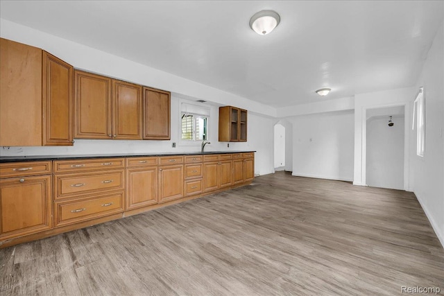 19966 Lindsay St, Detroit, MI 48235 - kitchen featuring arched walkways, brown cabinets, light wood-style flooring, and glass insert cabinets