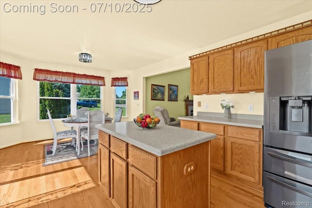 12366 Orchard Wood Dr, Fenton, MI 48430 - kitchen featuring stainless steel fridge, light countertops, light wood-style floors, and a kitchen island