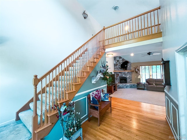 5580 Birch Ln, Davisburg, MI 48350 - stairs featuring a towering ceiling, a stone fireplace, wood finished floors, and a ceiling fan