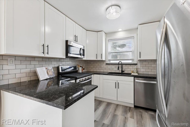 24360 Grove Ave, Eastpointe, MI 48021 - kitchen with stainless steel appliances, dark stone countertops, white cabinetry, and a peninsula