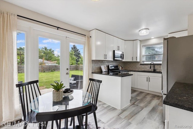 24360 Grove Ave, Eastpointe, MI 48021 - kitchen with appliances with stainless steel finishes, dark countertops, decorative backsplash, white cabinetry, and french doors