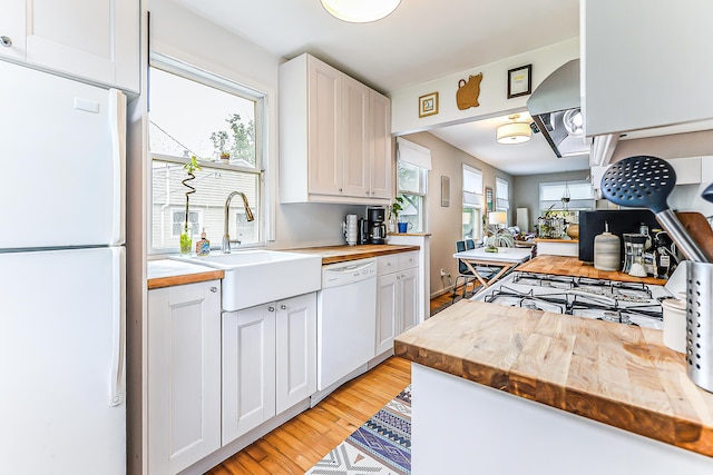 110 Fairview Dr, Ann Arbor, MI 48103 - kitchen featuring white appliances, butcher block counters, light wood finished floors, white cabinetry, and range hood