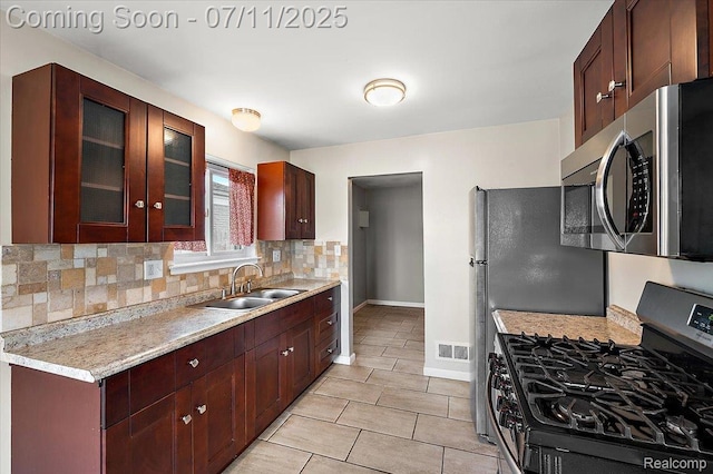 27043 Lorenz St, Madison Heights, MI 48071 - kitchen featuring appliances with stainless steel finishes, decorative backsplash, light countertops, light tile patterned flooring, and glass insert cabinets