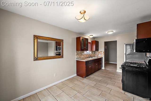 27043 Lorenz St, Madison Heights, MI 48071 - kitchen featuring stainless steel microwave, black gas range oven, light countertops, and decorative backsplash