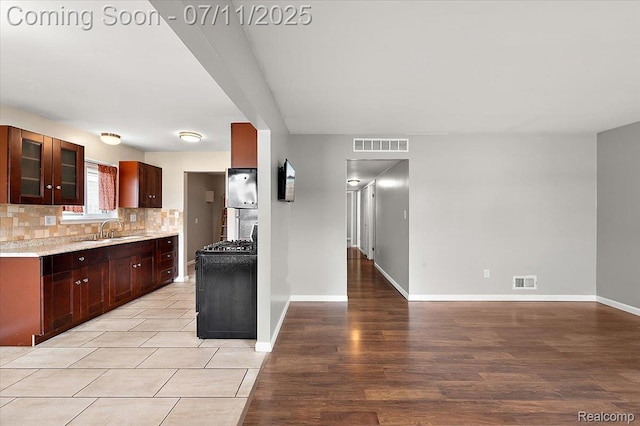 27043 Lorenz St, Madison Heights, MI 48071 - kitchen featuring gas stove, tasteful backsplash, glass insert cabinets, and light wood-style flooring