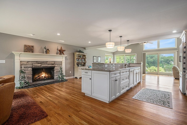 26794 Dutch Settlement St, Dowagiac, MI 49047 - kitchen with open floor plan, a stone fireplace, wood finished floors, white cabinetry, and a ceiling fan