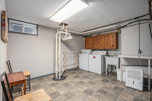 26794 Dutch Settlement St, Dowagiac, MI 49047 - laundry area featuring cabinet space, washing machine and dryer, concrete block wall, and stone finish flooring