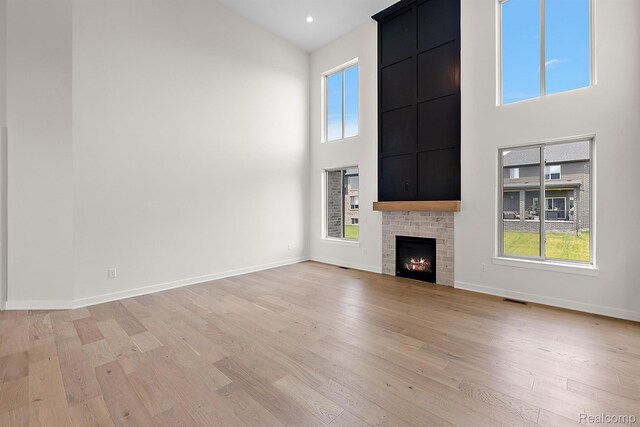 53650 Romeo Plank Rd, Macomb, MI 48042 - unfurnished living room with a high ceiling, light wood-type flooring, healthy amount of natural light, and a fireplace