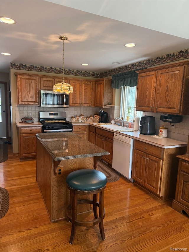 35851 Ireneus Dr, New Baltimore, MI 48047 - kitchen with stainless steel appliances, tasteful backsplash, brown cabinets, light wood-type flooring, and a kitchen island