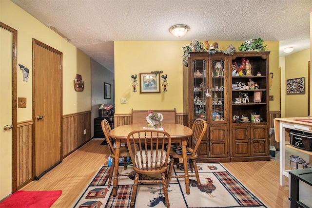5100 Holton Duck Lake Rd, Twin Lake, MI 49457 - dining space with a wainscoted wall, light wood-style flooring, a textured ceiling, and wooden walls