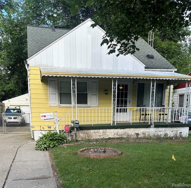 967 Hubbard Ave, Flint, MI 48503 - view of front of house featuring board and batten siding, roof with shingles, covered porch, and a front lawn