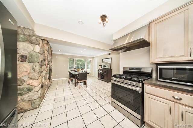 6730 Halyard Rd, Bloomfield Hills, MI 48301 - kitchen featuring stainless steel appliances, dark countertops, light tile patterned floors, wall chimney exhaust hood, and cream cabinetry
