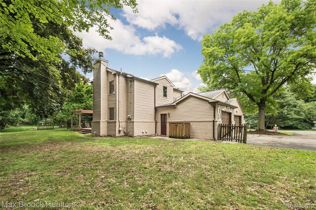 6730 Halyard Rd, Bloomfield Hills, MI 48301 - view of side of property featuring a chimney, an attached garage, a lawn, asphalt driveway, and brick siding
