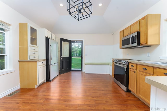405 Garden Ln, Fowlerville, MI 48836 - kitchen with appliances with stainless steel finishes, a chandelier, light countertops, vaulted ceiling, and wood finished floors